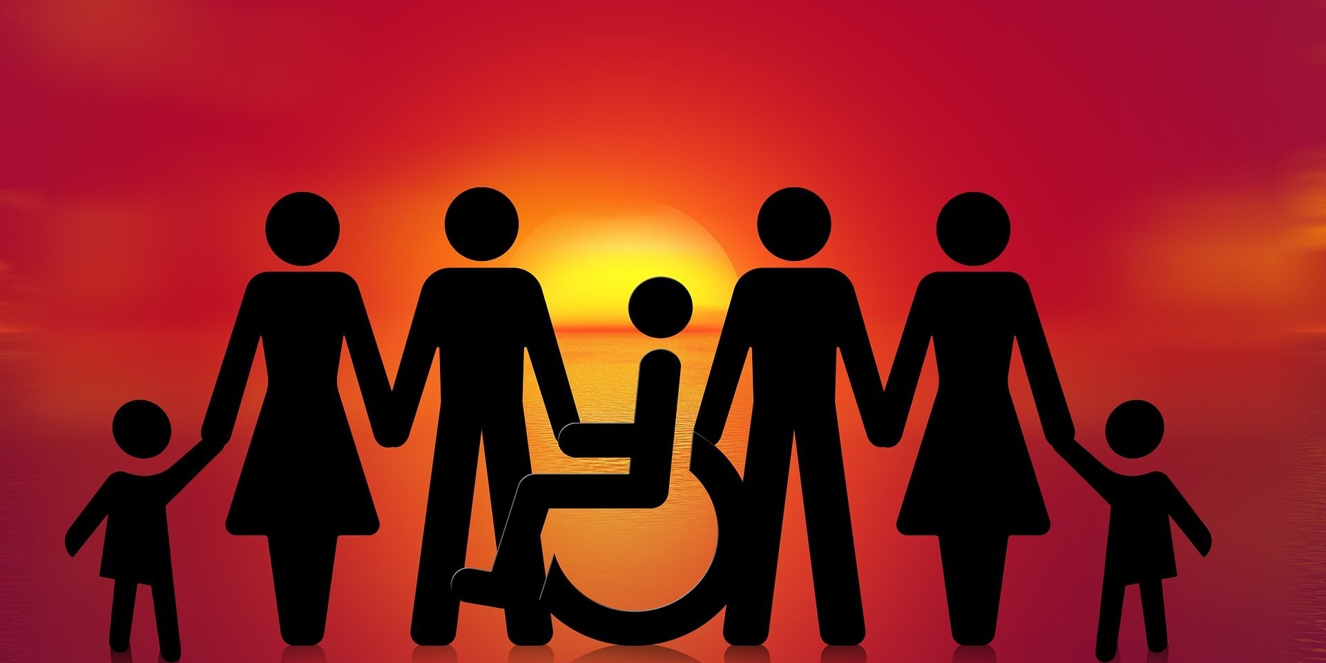 Familie mit Rollstuhl vor Sonnenuntergang am Meer