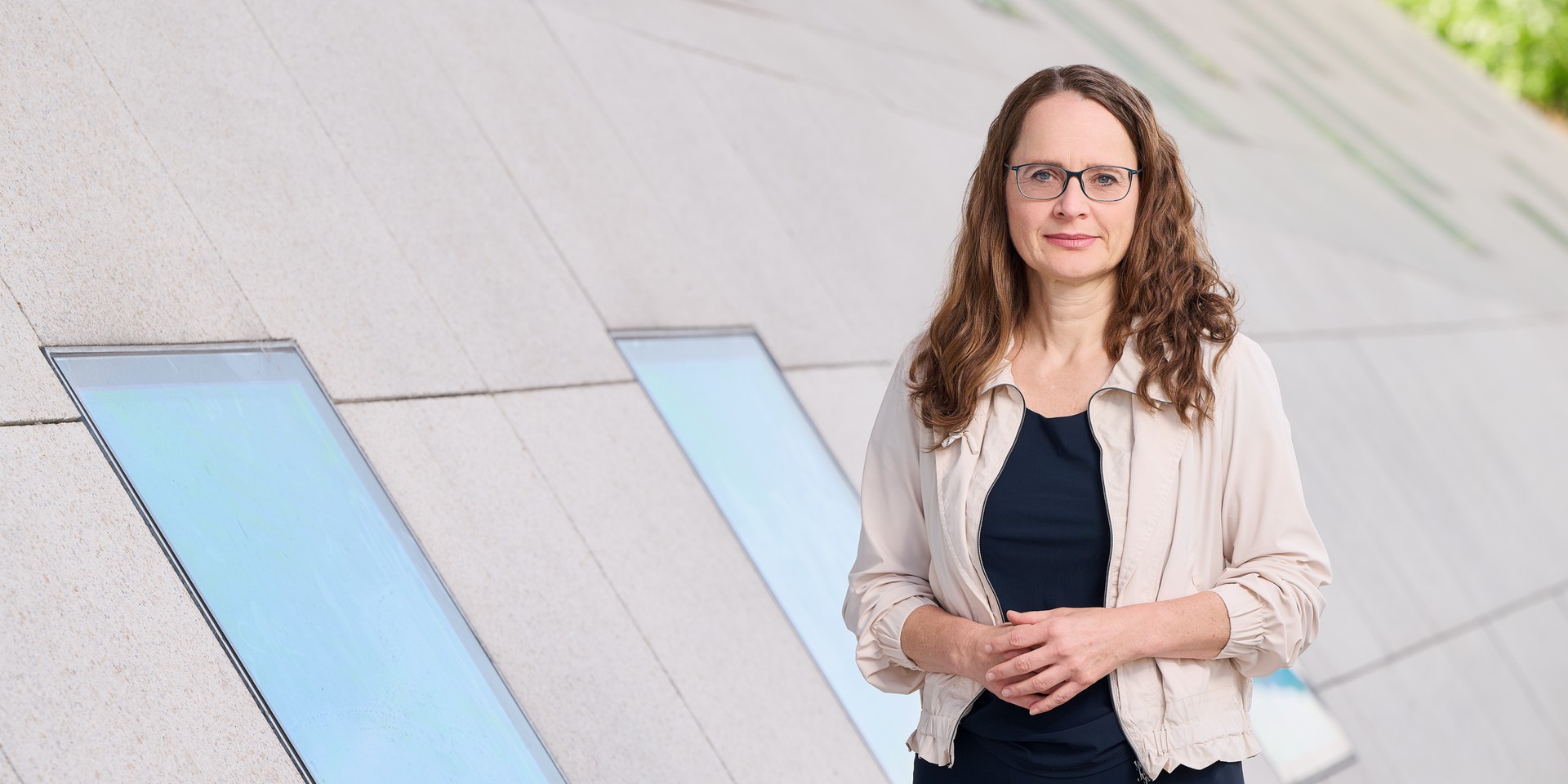 Frau mit Brille vor moderner Fassade mit Fenstern